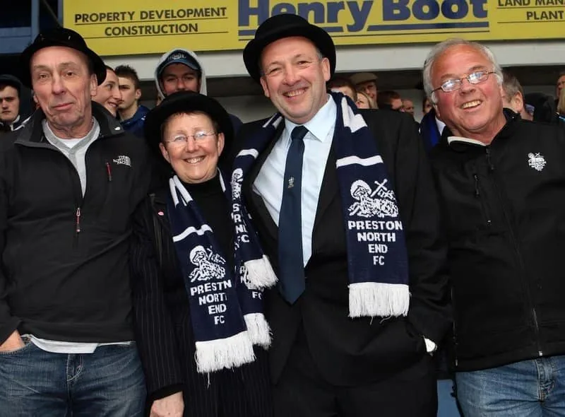 Supporters in scarves and bowlers smiling for the camera.