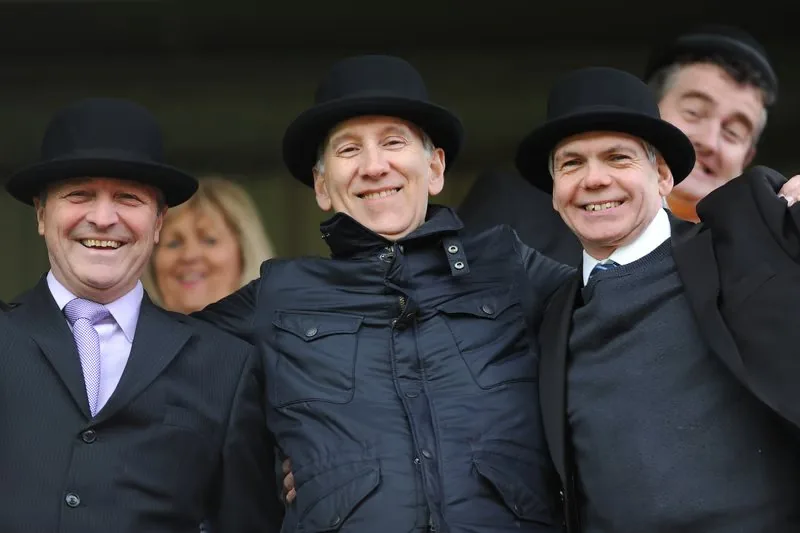 Three Preston supporters in bowlers and suits smiling outside the ground.